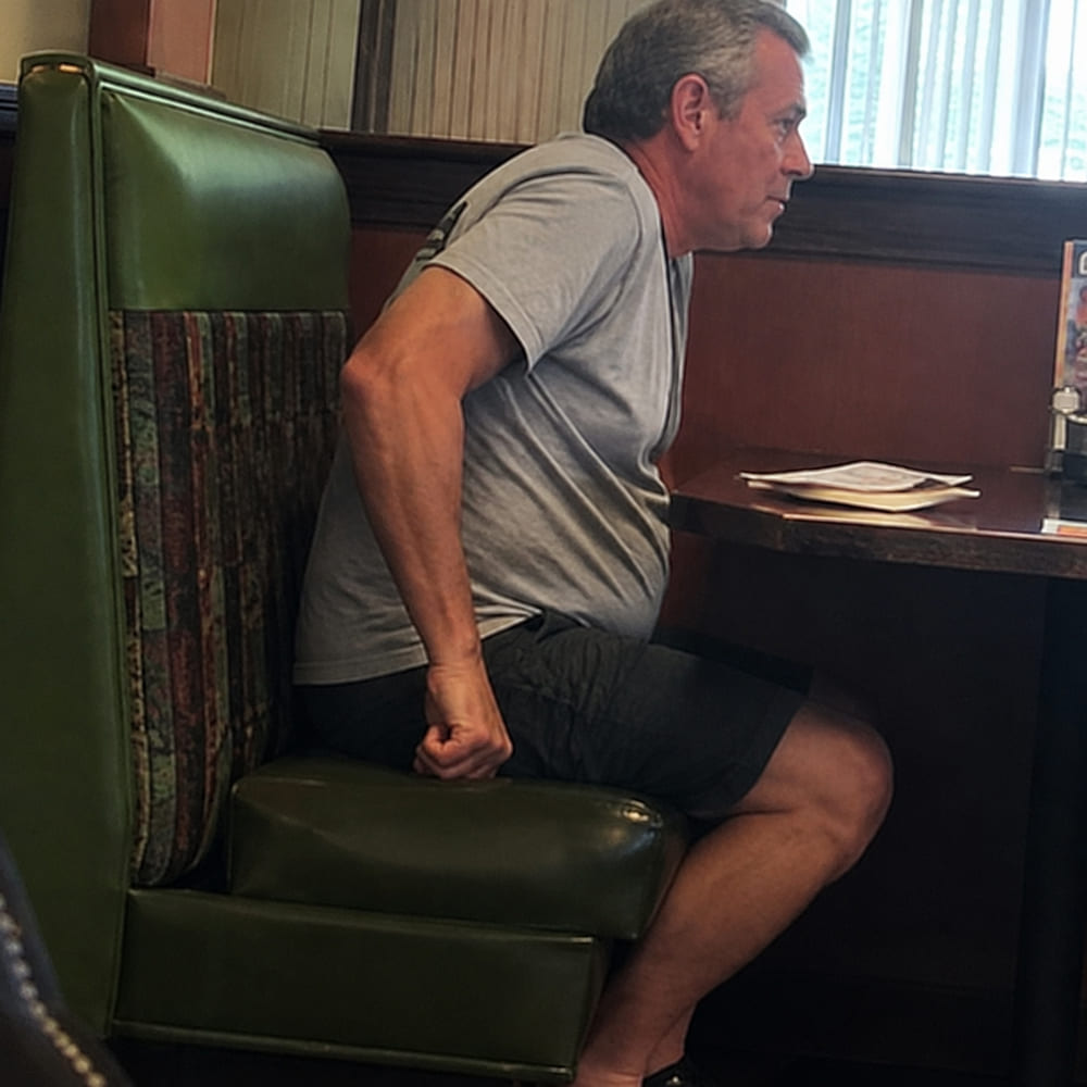 A man adjusting his position on a restaurant seat