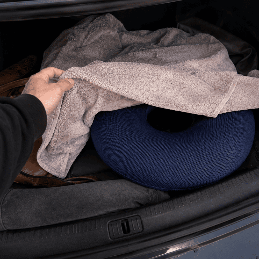 A donut cushion under a towel in a car trunk